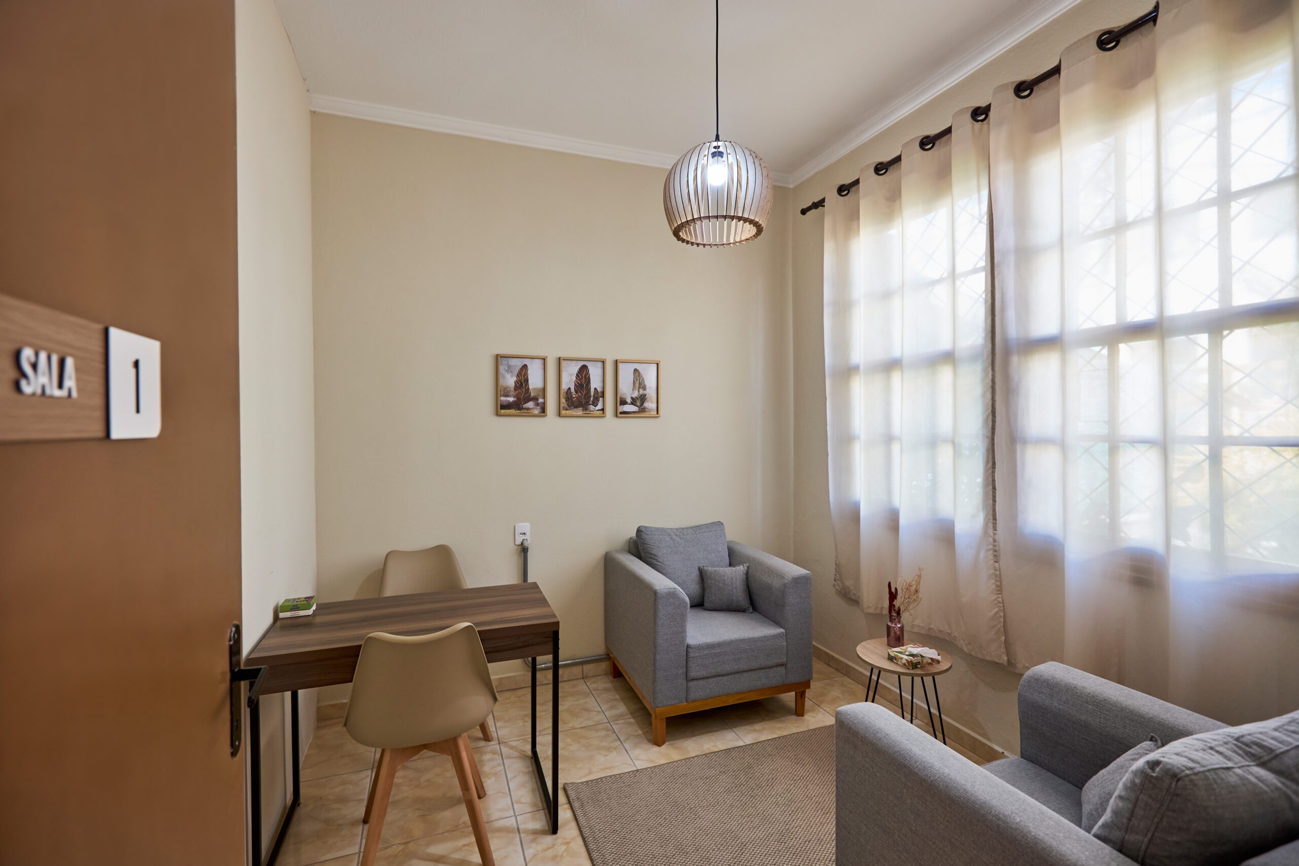 Sala 1 da Casa Gê, ideal para aluguel de consultório por hora em Campinas, com poltronas confortáveis, mesa e iluminação natural.